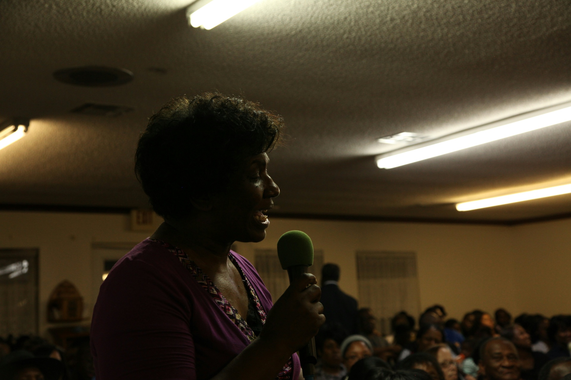 Woman addressing a community audience with a microphone